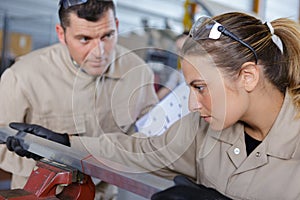 Female worker clamps metal in vice