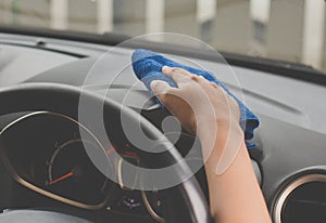 Female worker cleaning car inside dashboard