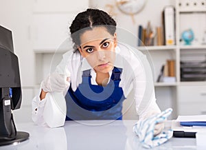 Female worker cleaning desk in office