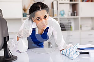 Female worker cleaning desk in office