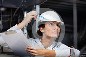 female worker with clipboard inspecting roofspace