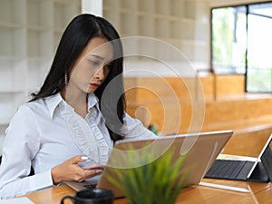 Female worker concentrating on her work with laptop in co working space