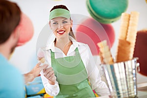 Female worker in confectionery giving ice cream to customer