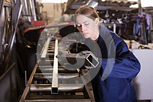 Female worker cuts metal profile pipe on a band saw