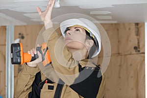 Female worker drilling ceiling