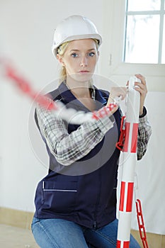 female worker erecting barrier around indoor work site