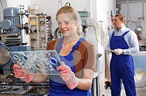 Female worker of glass factory drilling bores on machine