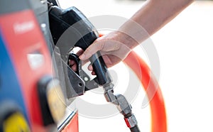 Female worker hand holding nozzle fuel fill oil into car tank at pump gas station