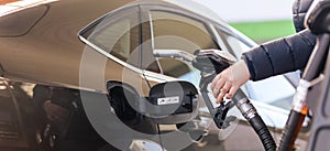 Female worker hand holding nozzle fuel fill oil into car tank at a pump gas station, For the concept transportation