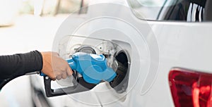 Female worker hand holding nozzle fuel fill oil into car tank at pump gas station, For the concept transportation power business