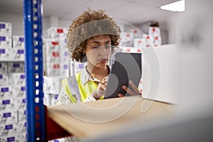 Female Worker In Logistics Distribution Warehouse Using Digital Tablet