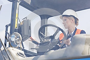 Female worker operating forklift truck in shipping yard