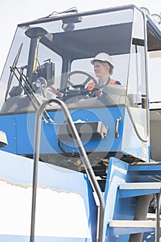 Female worker operating forklift truck in shipping yard