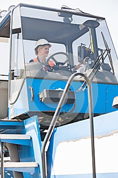 Female worker operating forklift truck in shipping yard