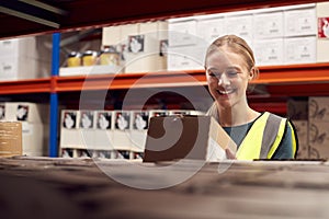 Female Worker Picking Box From Shelf Inside Warehouse 