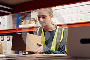 Female Worker Picking Box From Shelf Inside Warehouse 