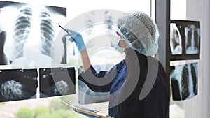 Female worker posing with digital tablet near x-ray scans