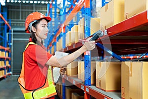 Female worker with protective vest and scanner, holds document, standing at warehouse of freight forwarding company, scanning qr
