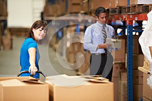 Female Worker Pulling Pallet In Warehouse