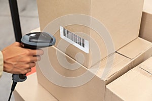 Female worker scanning package with barcode scanner in warehouse