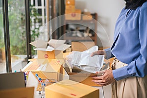 Female worker or seller packing roasted coffee beans in packaging ecommerce shipping order box for dispatching