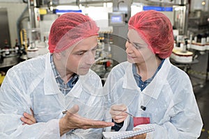 female worker showing clipboard to colleague in factory