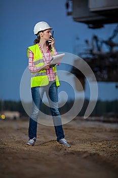 female worker talking on walie-talkie with folder photo