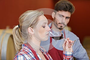 female worker testing red wine in cellar