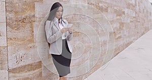 Female worker texting and leaning against wall