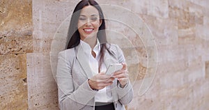 Female worker texting and leaning against wall