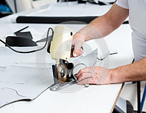 Female worker uses electric cutting fabric machine. Fabric industry production