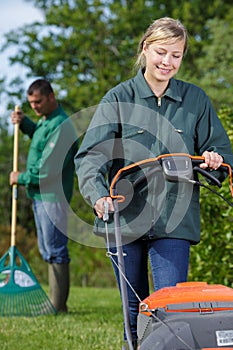 female worker using lawn mower for cutting green grass