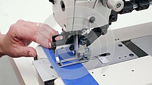 Female worker using a sewing machine to cut holes for buttons