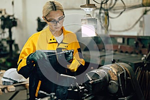 female worker using vernier caliper measuring metal part in lathe machine in heavy metal workshop