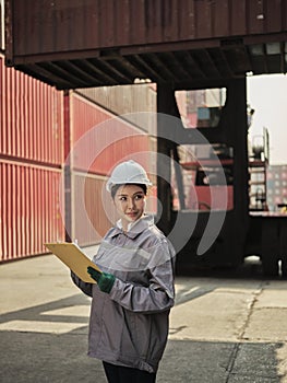 Female worker wearing safety helmet and working with container