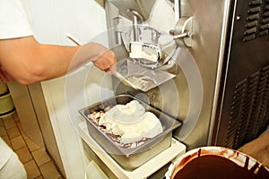 Female worker is working on ice cream maker machine. Producing vanilla ice cream with chocolate dressing.