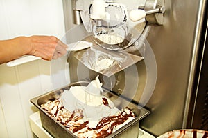 Female worker is working on ice cream maker machine. Producing vanilla ice cream with chocolate dressing.