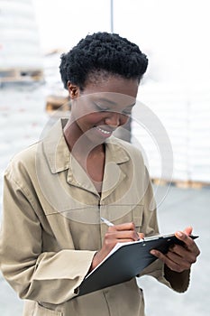 Female worker writing on clipboard in warehouse