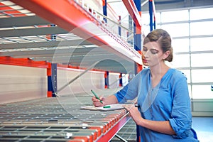 Female worker writing inventory at delivery depot warehouse