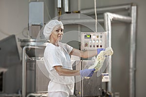 Female worker on yellow cheese production line in an industrial