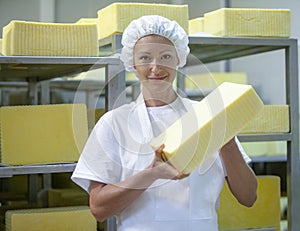 Female worker on yellow cheese production line in an industrial