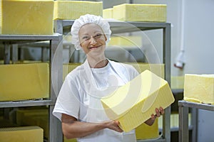 Female worker on yellow cheese production line in an industrial