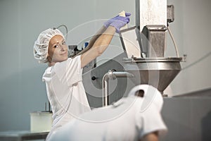 Female worker on yellow cheese production line in an industrial