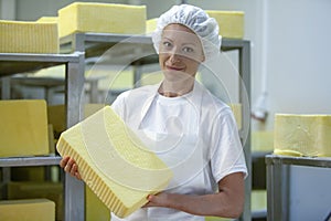 Female worker on yellow cheese production line in an industrial