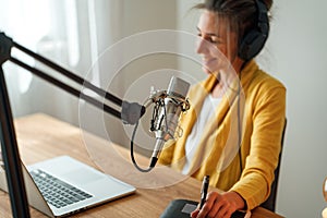 Female working at broadcast studio homemade. Focus on microphone