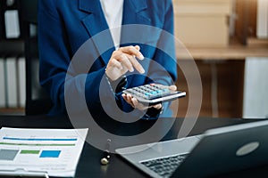 Female working on desk office with using a calculator to calculate tax