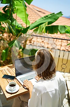 female working remotely on the laptop computer while sitting on balcony hotel