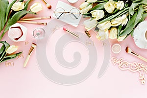 Female workspace with tulip flowers bouquet, golden accessories, diary, on pink background. Flat lay women`s office desk