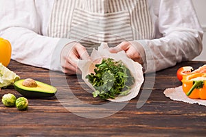 Female wrapping green dill and parsley into beeswax wraps