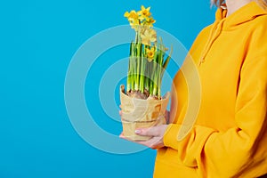 Female in yellow hoodie with daffodil flowers